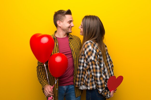 Paare am Valentinstag, der ein Herzsymbol und -ballone hält