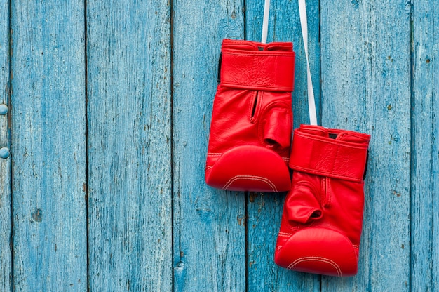 Paare der roten Boxhandschuhe, die an einem Nagel hängen