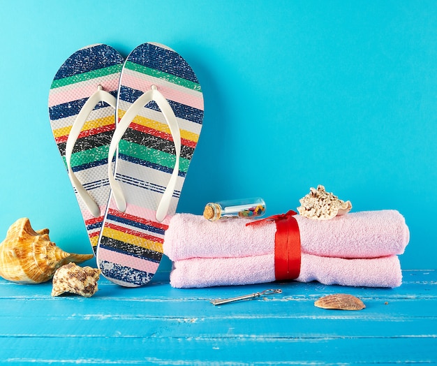 Paare der weiblichen Strandpantoffel und des rosa Tuches auf Blau