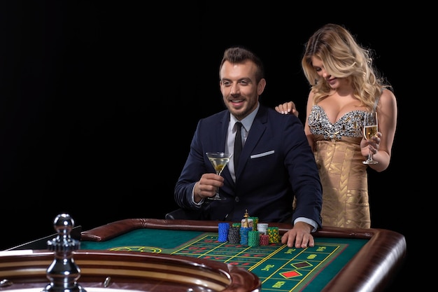 Paare, die am Roulette-Tisch im Casino spielen. Schwarzer Hintergrund. Aufregung. Risiko. Glück