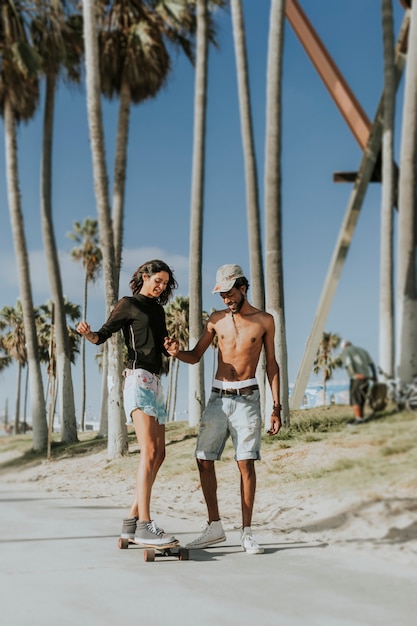 Paare, die am Venedig-Strand longboarding sind