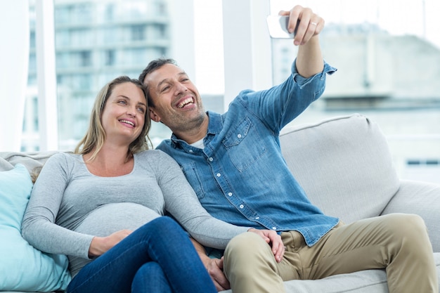 Paare, die auf Sofa sitzen und ein selfie auf Smartphone nehmen