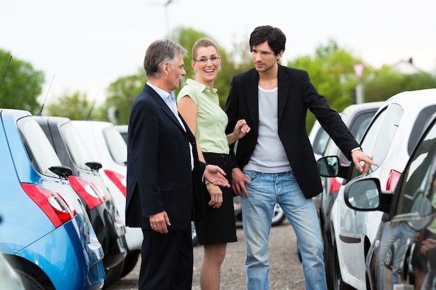 Paare, die Auto auf Yard des Händlers betrachten