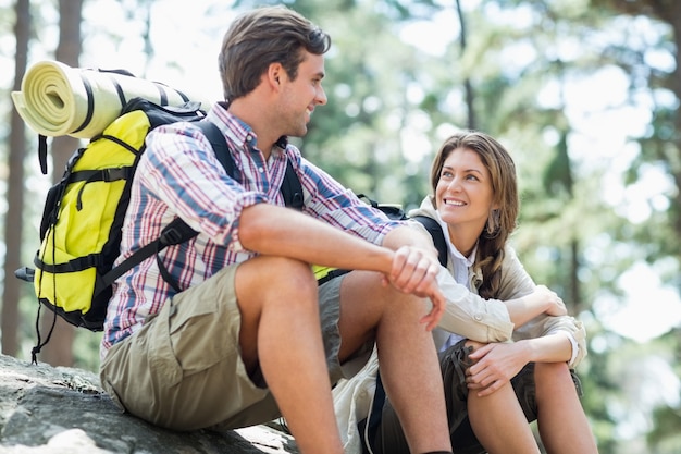 Paare, die beim Sitzen auf Felsen vertraulich schauen