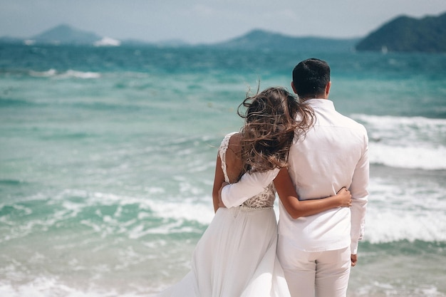 Paare, die das Meer in der Hochzeitskleidung betrachten. Phuket. Thailand. Rückansicht