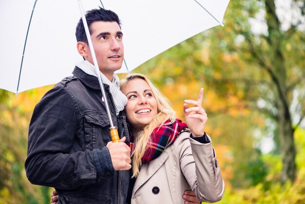 Paare, die den Herbsttag trotz des Regens spazieren genießen