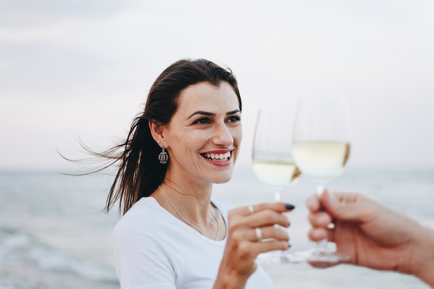 Paare, die ein Glas Wein durch den Strand genießen