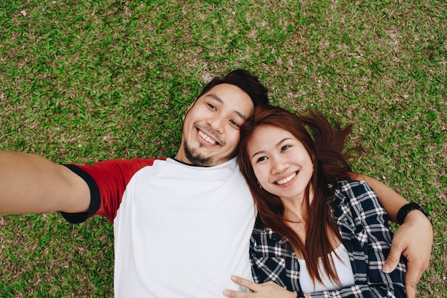 Paare, die ein selfie im Gras nehmen