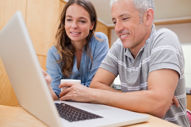 Paare, die einen Laptop beim Trinken des Kaffees verwenden