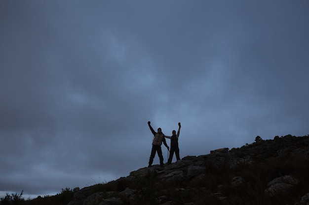 Paare, die Hände auf felsiger Landschaft gegen Himmel nachts anheben