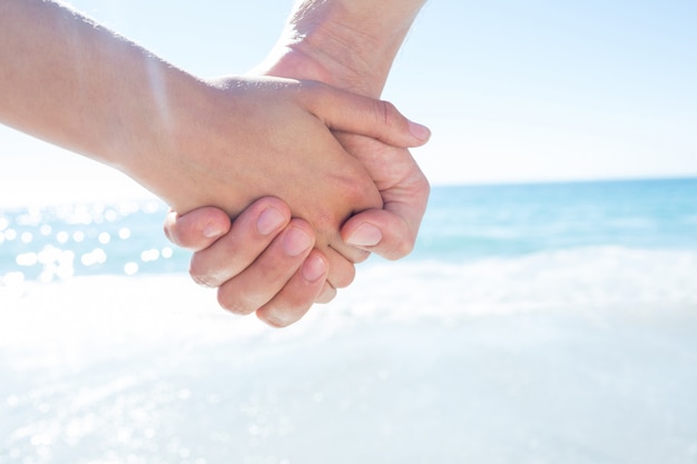 Paare, die Hand in Hand am Strand gehen