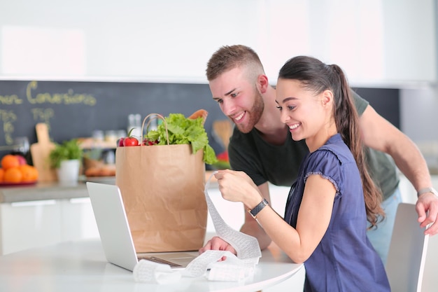 Paare, die ihre Rechnungen mit Laptop in der Küche zu Hause bezahlen