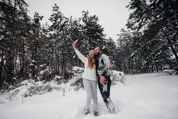 Paare, die mit Schnee im Wald spielen.