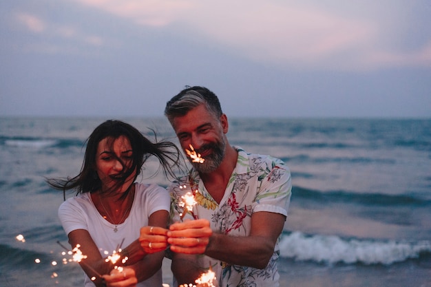 Paare, die mit Wunderkerzen am Strand feiern