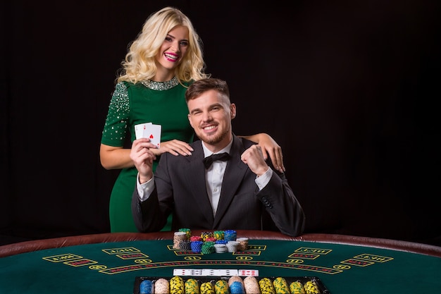 Paare, die Poker am grünen Tisch spielen. Das blonde Mädchen und ein Typ im Anzug. glücklicher Sieg, zwei