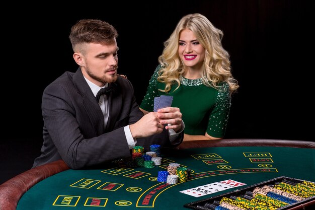 Paare, die Poker am grünen Tisch spielen. Das blonde Mädchen und ein Typ im Anzug.