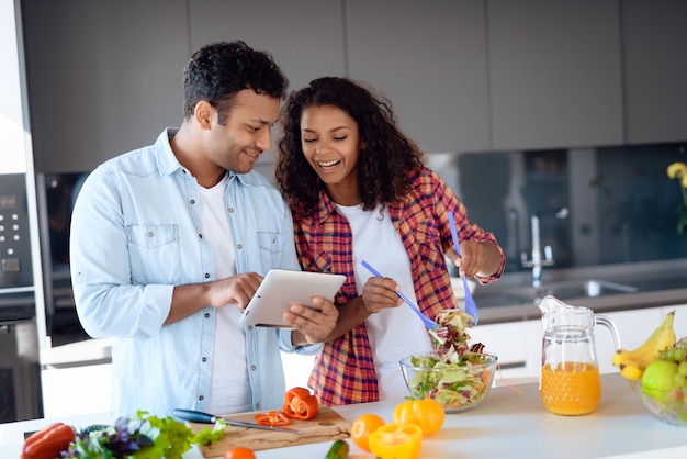 Paare, die Salat kochen und Tablette auf Küche verwenden