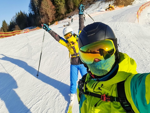 Paare, die selfie am sonnigen tag des skigebiets mit spaß machen