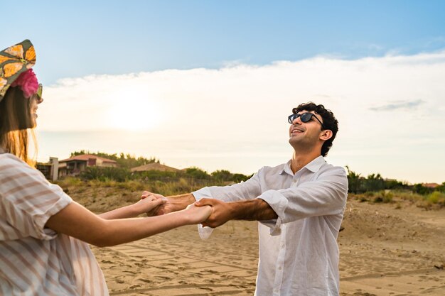 Paare, die sich zusammen Händchen haltend im Strand drehen. Romantik und Urlaubskonzept.