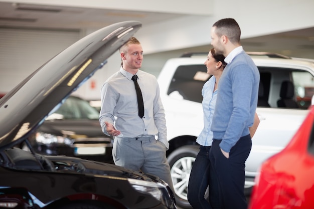 Paare, die vor einem Automotor des offenen Autos stehen