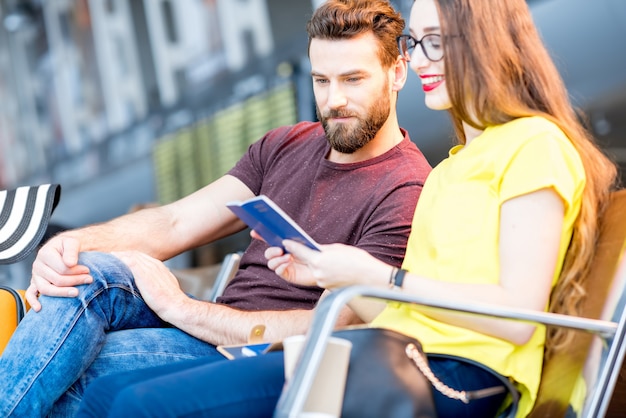 Paare, die während ihres Sommerurlaubs im Wartezimmer des Flughafens Pässe überprüfen