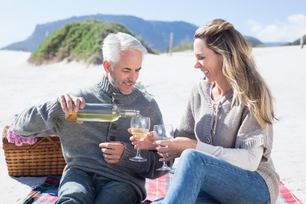 Paare, die Weißwein auf Picknick am Strand genießen