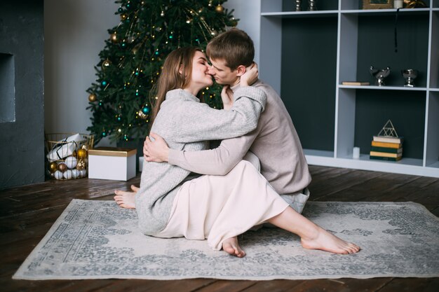 Paare, die zu Hause nahe Weihnachtsbaum, neues Jahr sitzen