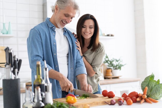Paare, die zu Hause zusammen in ihrer Küche kochen.