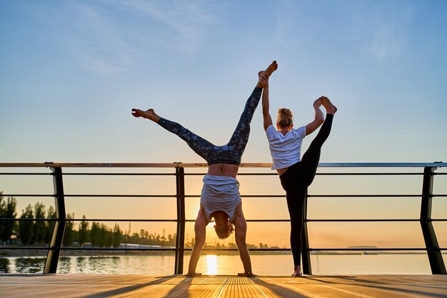 Paare, die zusammen Yoga auf der Natur im Freien praktizieren, Morgenübungen bei Sonnenaufgang