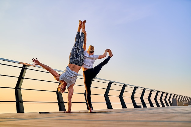 Paare, die zusammen Yoga auf der Natur im Freien praktizieren, Morgenübungen bei Sonnenaufgang