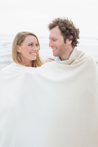 Paare eingewickelt in der Decke am Strand