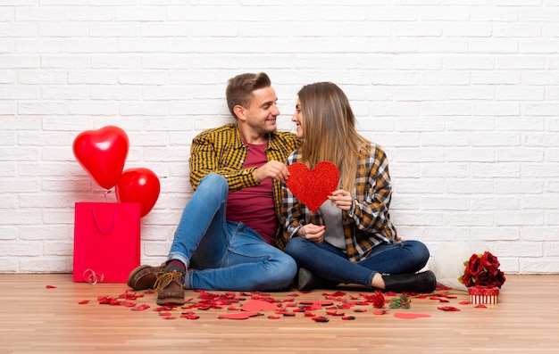 Paare im Valentinstag an einem Herzsymbol zuhause halten