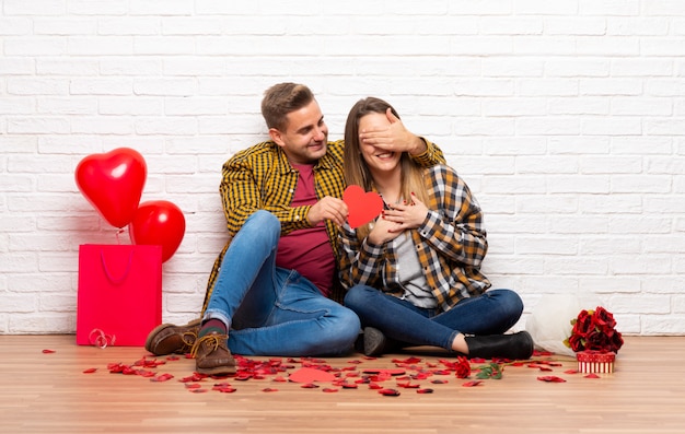 Paare im Valentinstag an einem Herzsymbol zuhause halten