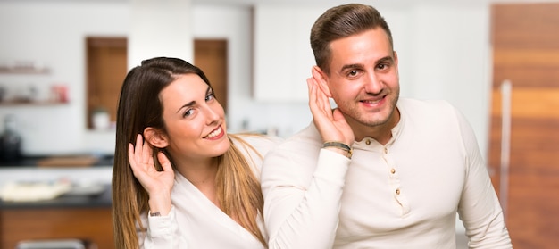 Paare im Valentinstag hörend etwas in einem Haus