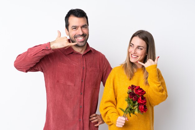 Paare in Valentine Day, der Blumen über der lokalisierten Wand macht Telefongeste hält. Rufen Sie mich zurück zu unterzeichnen