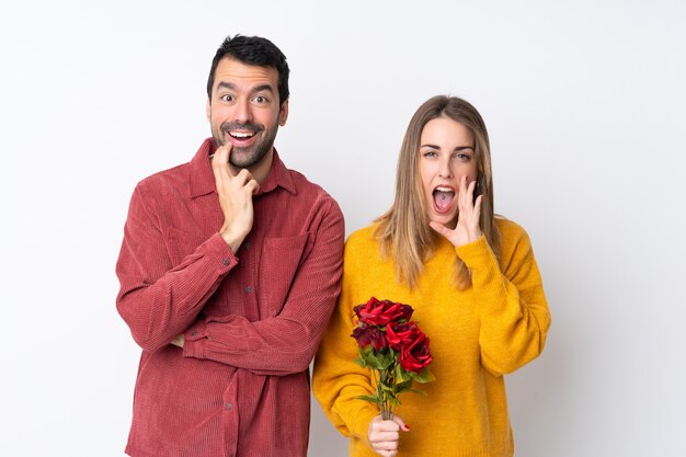 Paare in Valentine Day, der Blumen über lokalisierter Wand überrascht und beim Schauen recht entsetzt hält