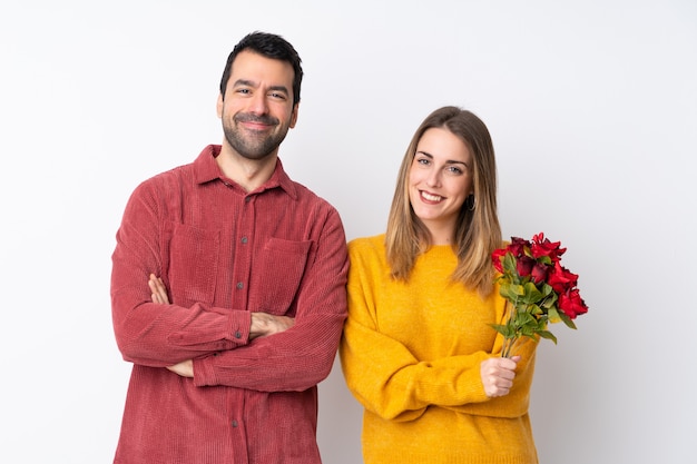Paare in Valentine Day-Holdingblumen über der lokalisierten Wand, welche die Arme gekreuzt in der Frontposition hält