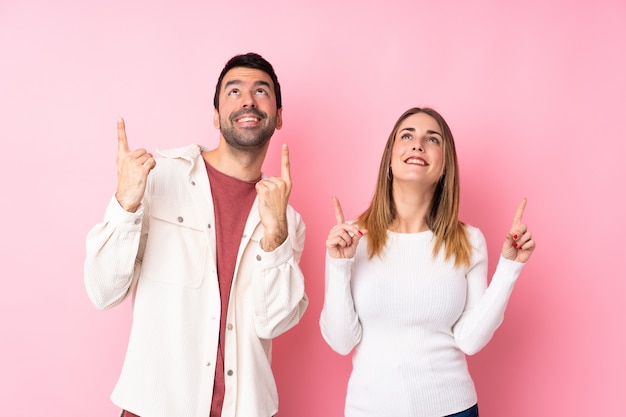 Paare in Valentine Day über der lokalisierten rosa Wand, die mit dem Zeigefinger eine großartige Idee zeigt