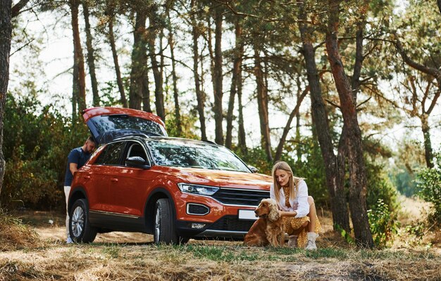 Paare mit Hund haben ein Wochenende draußen im Wald mit dem Auto.