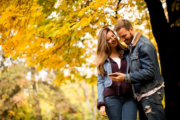 Paare mit Telefon im Herbstpark