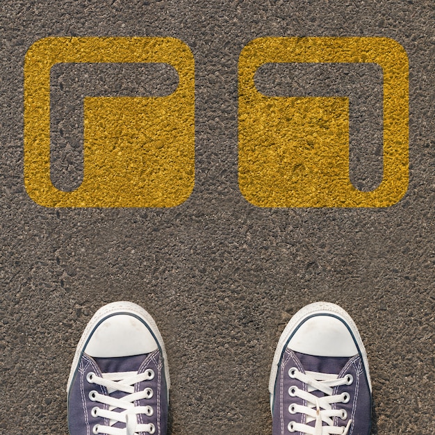 Paare Schuhe, die auf einer Straße mit gelbem Zweiwegpfeil stehen