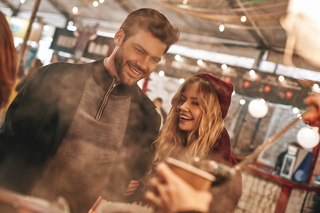 Paare trinken draußen. Junges Paar trinkt Glühwein auf dem Streetfood-Markt. Kalte Jahreszeit. Nahaufnahme des Paares