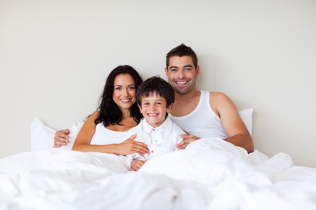 Paare und Sohn zusammen im Bett, das an der Kamera lächelt