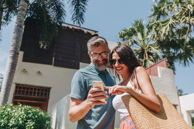 Paare unter Verwendung ihres Telefons während im Urlaub