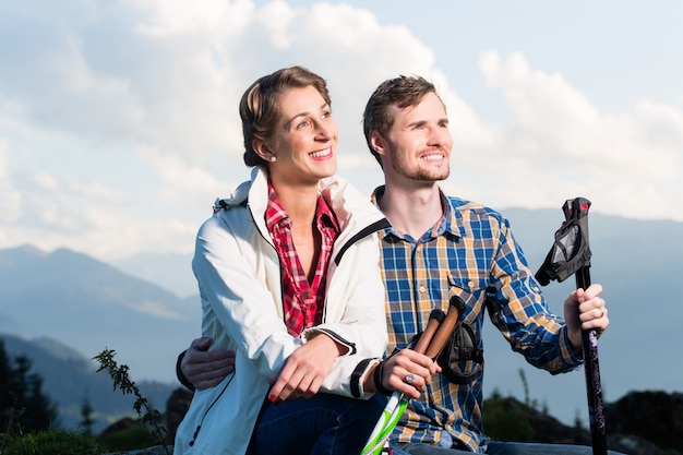 Paare, welche die Ansicht wandert in den alpinen Bergen genießen