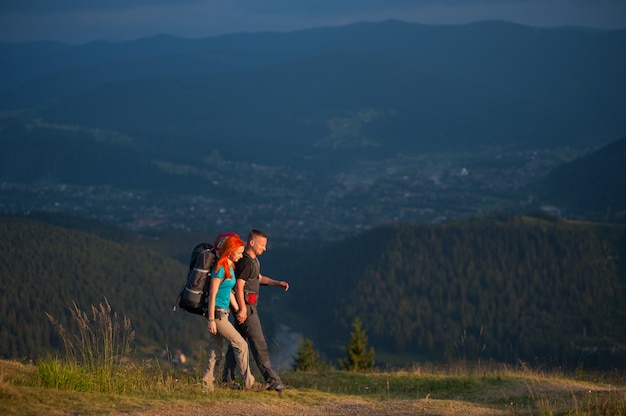 Paarwanderer mit Rucksäcken gehen entlang einer Straße