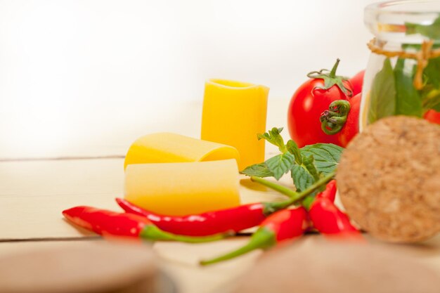 Paccheri-Pasta mit roten Chilischoten und Tomaten mit Kräutern auf weißem Hintergrund