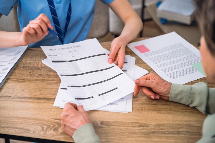Foto paciente a verificar os registos médicos, a ler e a assinar documentos no consultório do médico