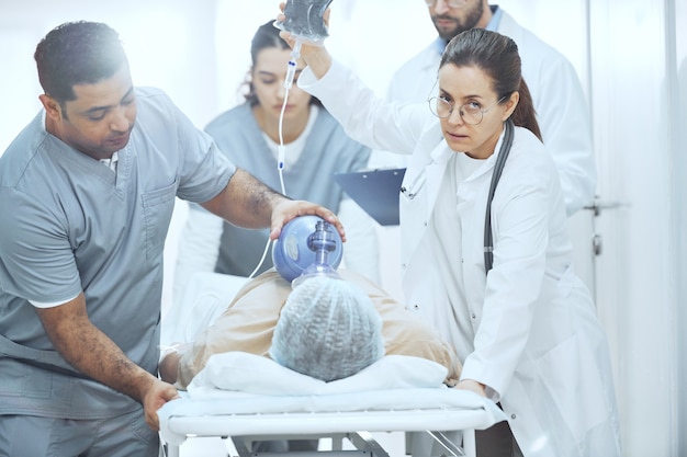 Paciente acostado con máscara de oxígeno mientras los médicos realizan una reanimación con desfibrilador en el hospital