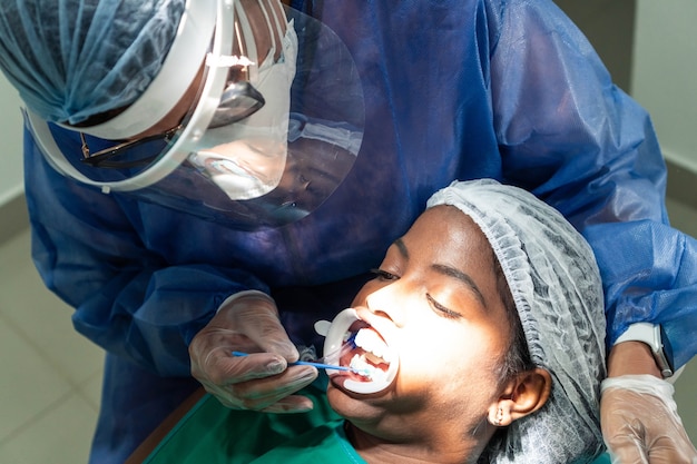 Paciente africano recebendo tratamento de clareamento pelo dentista